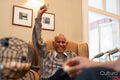 Smiling senior man raising arm during bingo game in nursing home