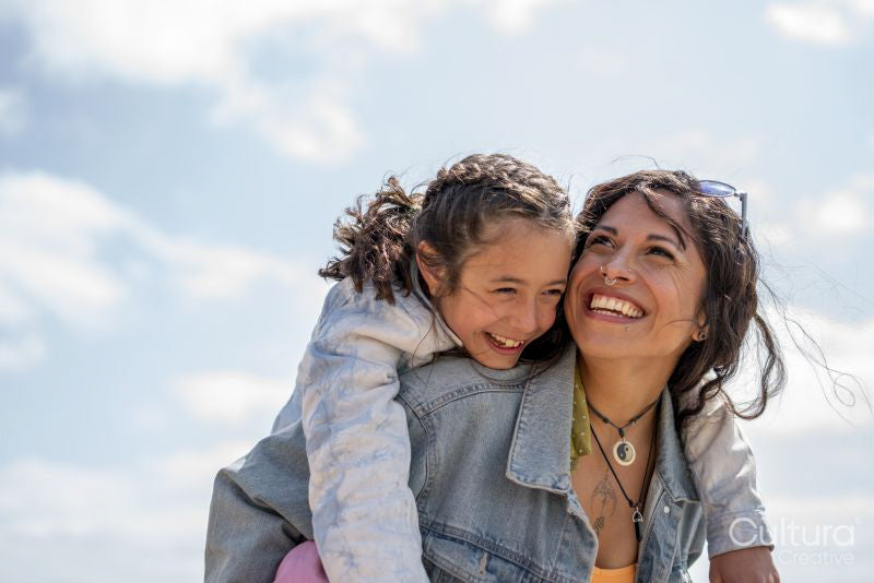 Smiling mother giving daughter piggyback ride