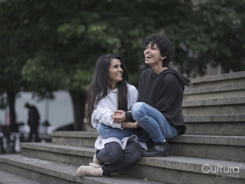 Female couple hugging on stairs in city