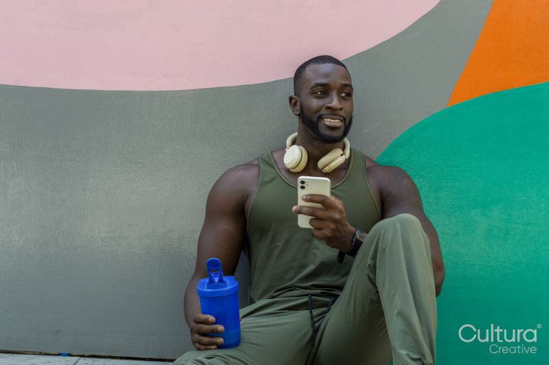 Mid adult man holding phone and plastic water container
