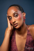 Woman in a burgundy dress with red earrings on a blue background