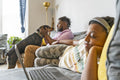 Girl using laptop on sofa, father with dog in background