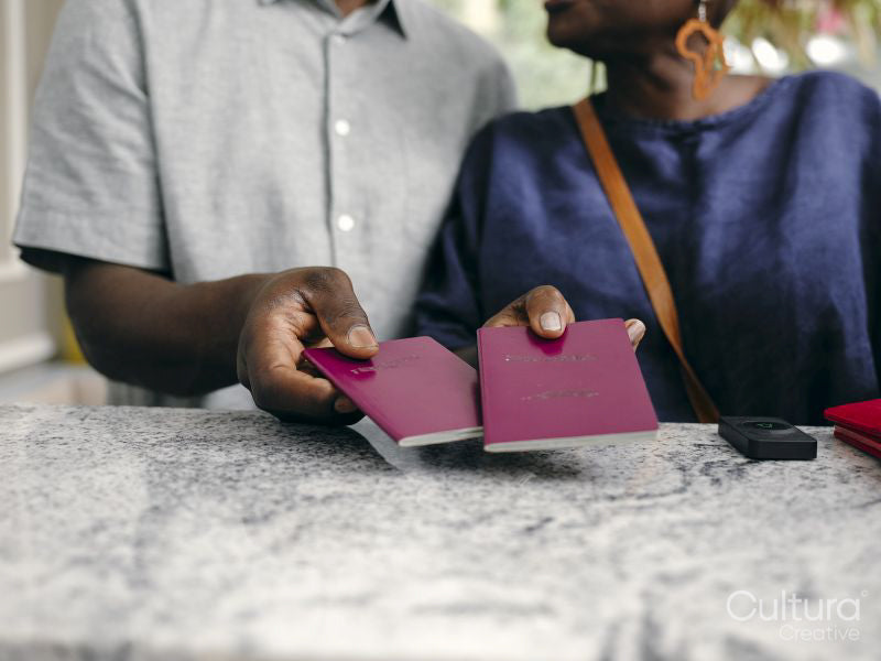 Close-up of mature couple holding passports at hotel front desk