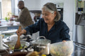 Two senior women preparing meal in kitchen