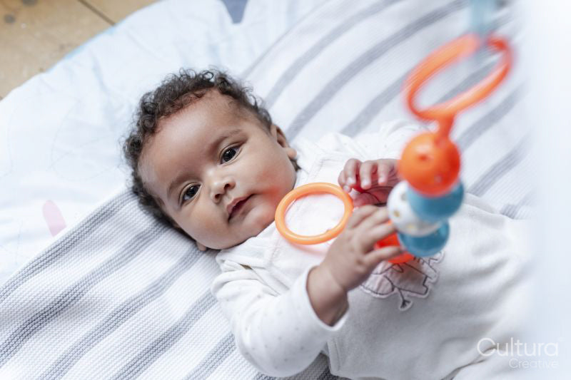 Baby girl looking at camera and holding toy