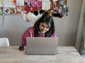 Woman working on laptop at home with cat on shoulder