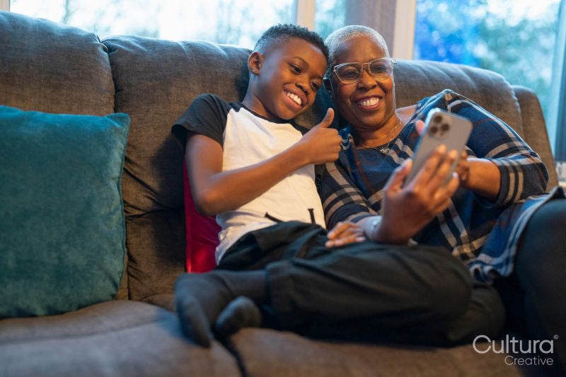 Grandmother and grandson with smart phone sitting on sofa