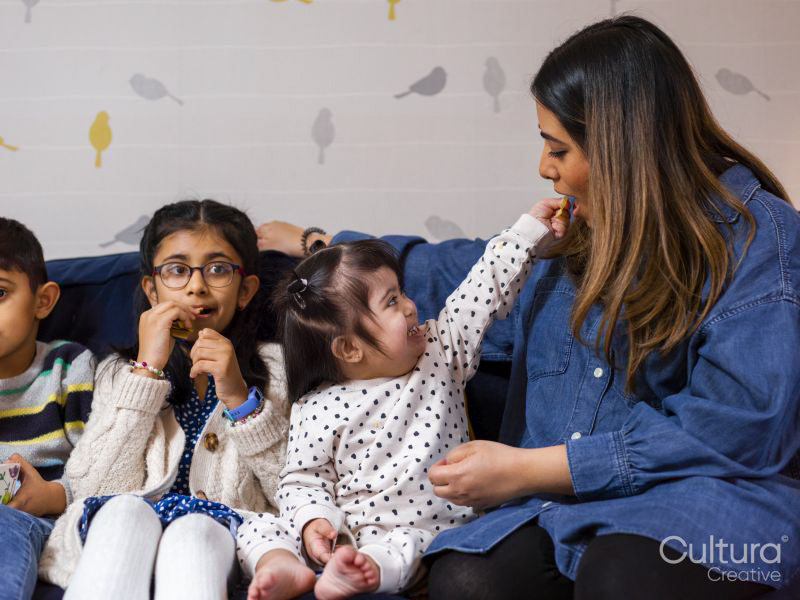 Mother with children sitting on sofa and eating snacks