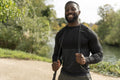 Portrait of smiling athletic man with jump rope in park