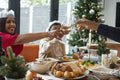 Family wearing paper crowns toasting during Christmas dinner