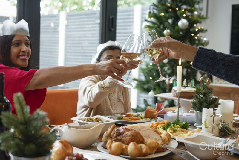 Family wearing paper crowns toasting during Christmas dinner