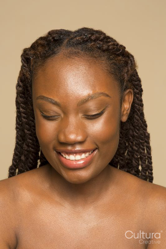 Studio portrait of smiling shirtless woman with braided hair