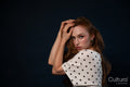Woman posing with hand on head in polka dot top studio portrait