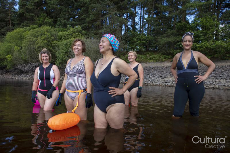 Smiling female friends standing in lake, Yorkshire, UK