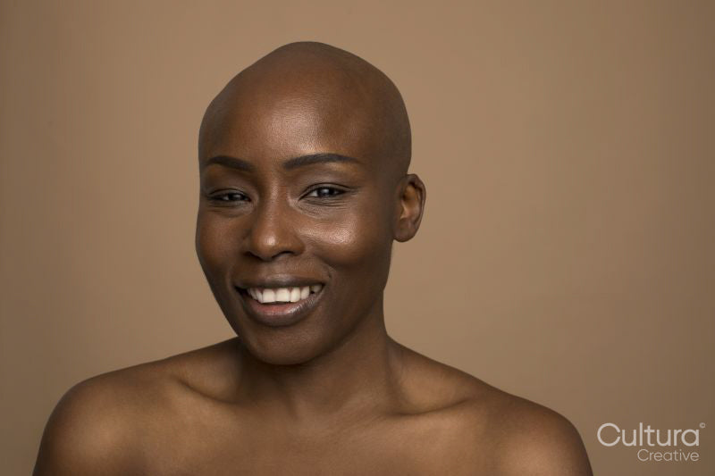 Studio portrait of smiling woman with shaved head