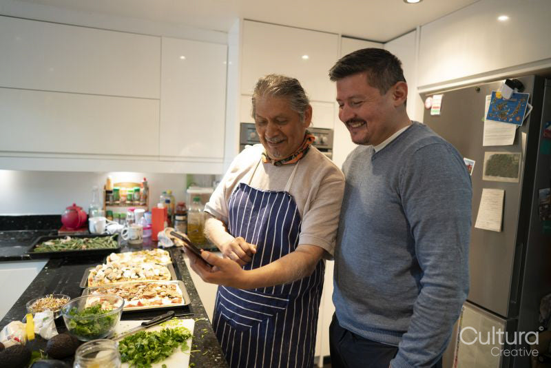 Father and adult son looking at smart phone in kitchen