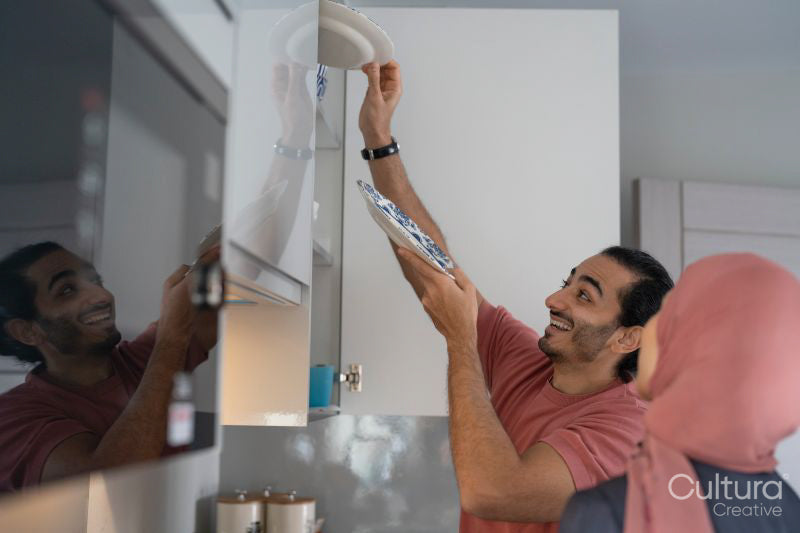 Smiling mid adult couple doing chores together in kitchen