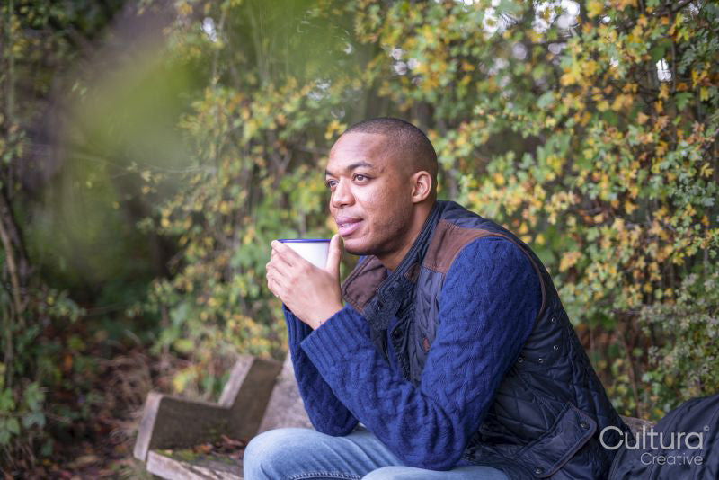 Man sitting on bench and having warm drink in nature at autumn