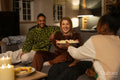 Smiling friends relaxing on sofa at home, sharing popcorn