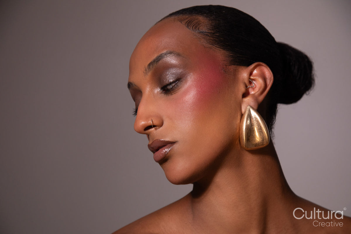 Studio portrait of a woman in a black dress and gold earrings