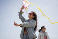 Mother and daughter flying kite on beach