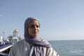 Portrait of Muslim woman looking at sea on sunny day