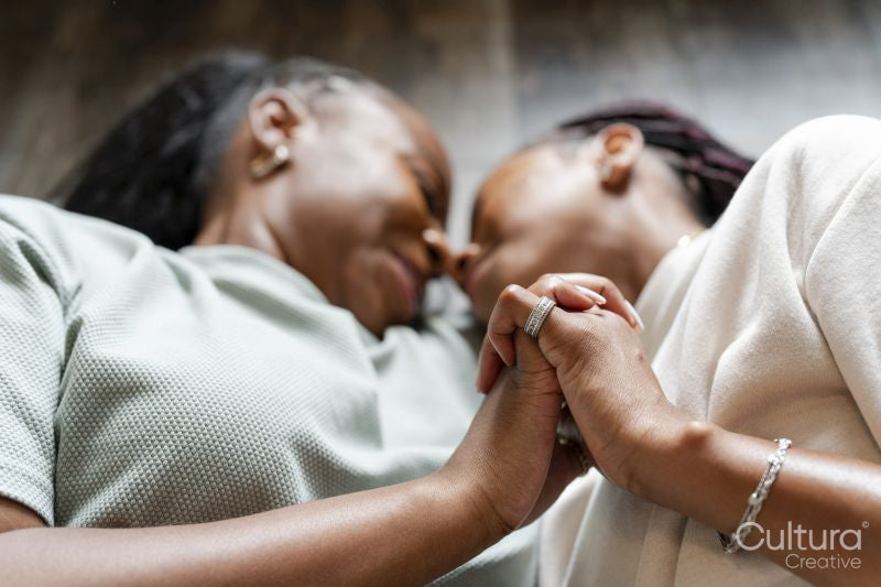 Close-up of couple holding hands while lying on floor