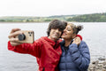Mother and son taking selfie by lake on hike