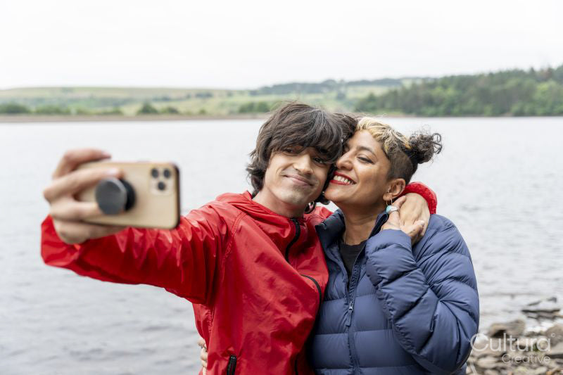 Mother and son taking selfie by lake on hike