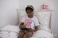 Girl with headphones and tablet sitting on bed
