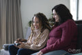 Two women sitting on sofa and playing video game