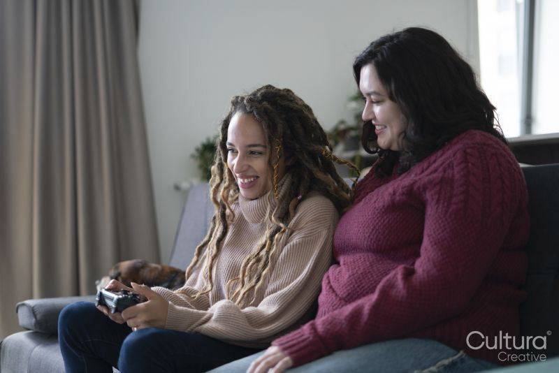 Two women sitting on sofa and playing video game