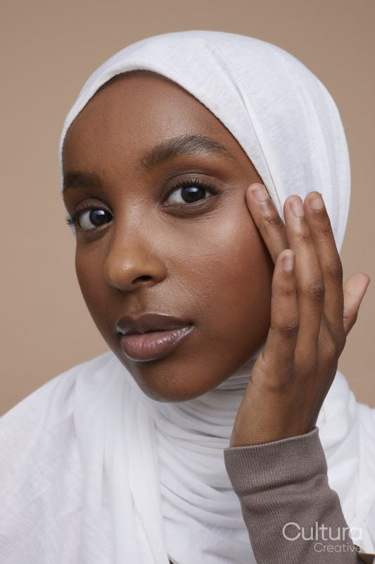 Studio portrait of young woman in white hijab touching face