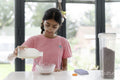 Girl pouring milk into bowl during breakfast