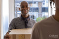 Smiling father and son entering house with cardboard boxes