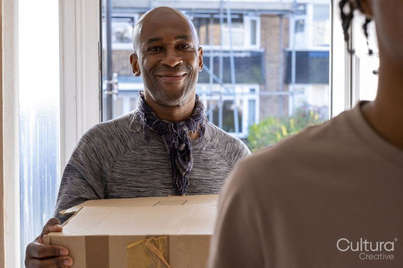 Smiling father and son entering house with cardboard boxes