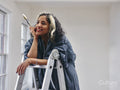 Smiling woman standing on ladder with paintbrush