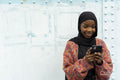 Smiling young woman wearing hijab looking at smart phone