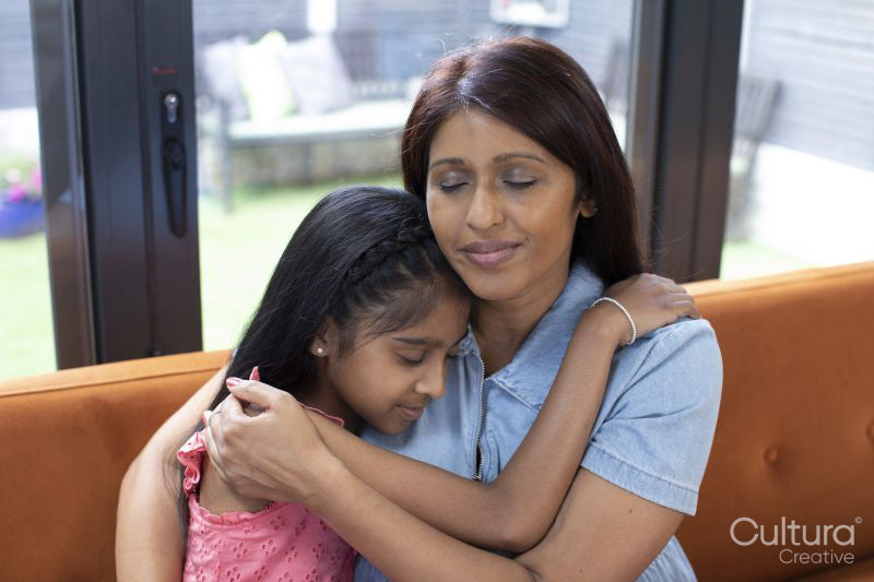 Smiling mother embracing daughter at home
