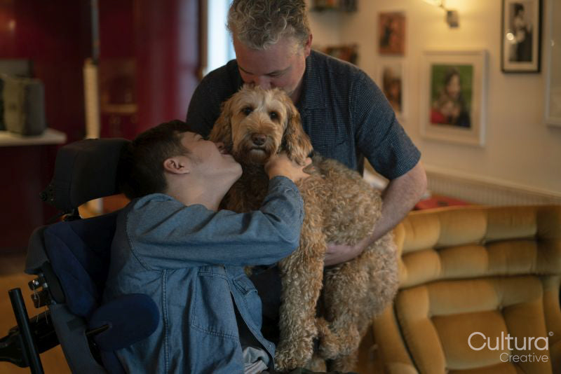 Father and disabled son cuddling dog