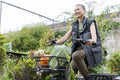 Smiling woman riding cargo electric trike loaded with homegrown vegetables