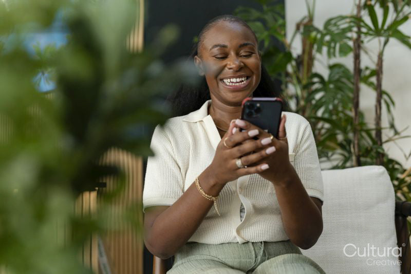 Happy woman with smartphone sitting in office lounge