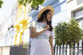 Smiling young woman in sun hat standing in street