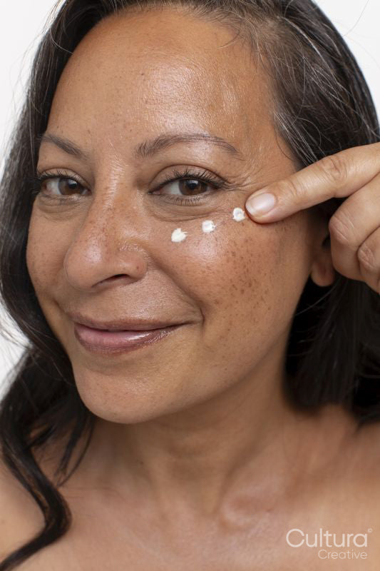 Studio portrait of smiling woman with dots of eye cream