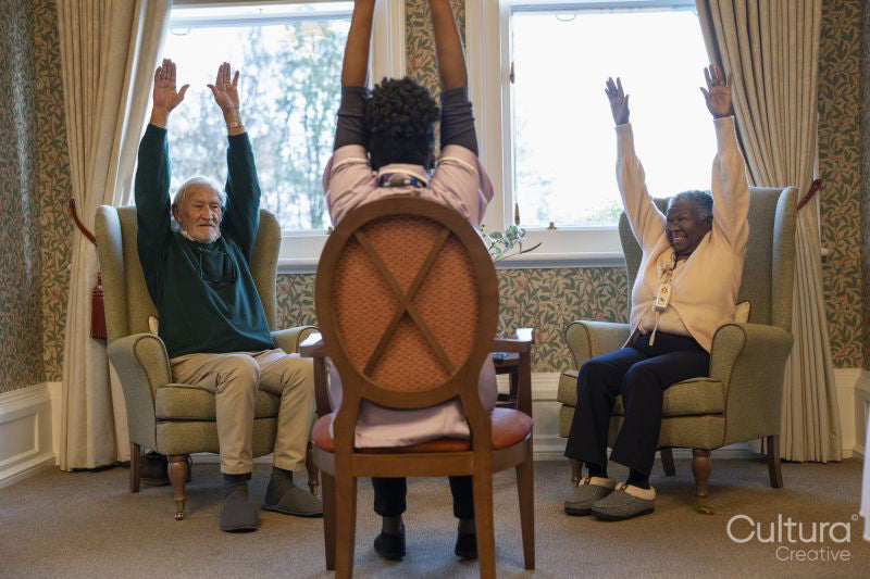 Smiling senior people exercising with nurse in nursing home