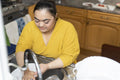 Young woman with down syndrome washing dishes at home