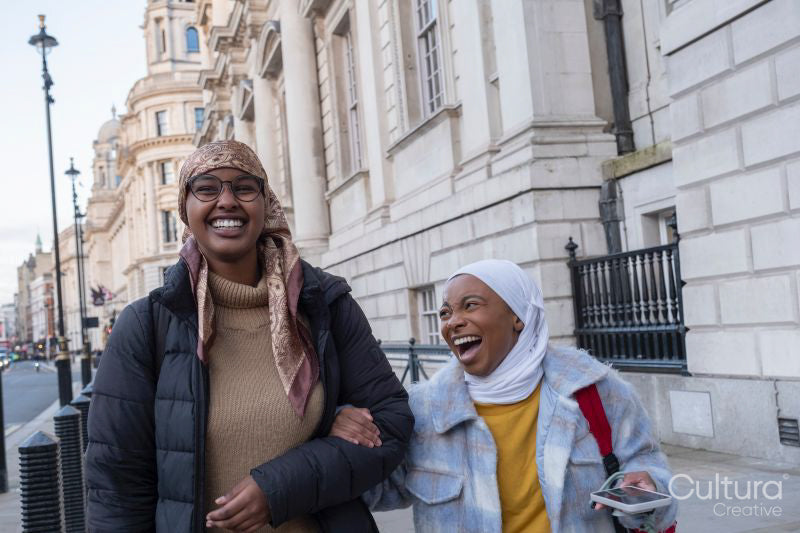 Smiling young female tourists in hijabs walking around city