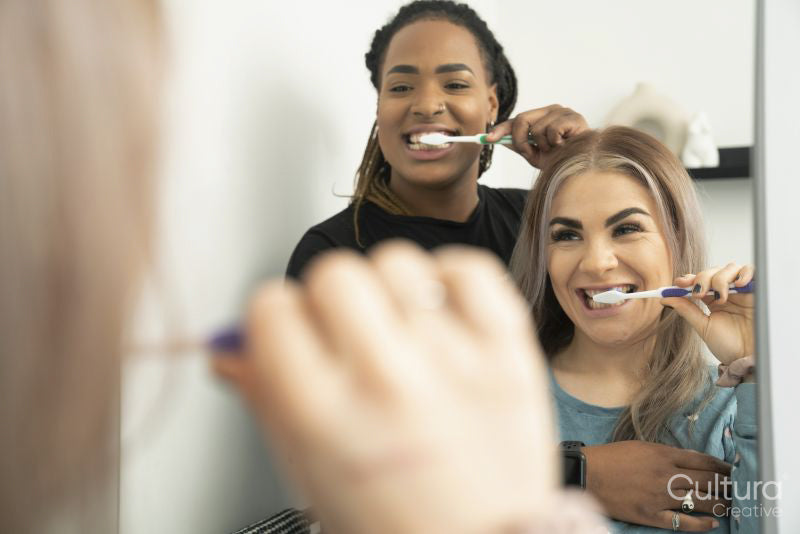 Two young women brushing teeth together