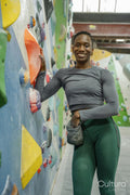 Portrait of smiling athletic woman at climbing wall at gym
