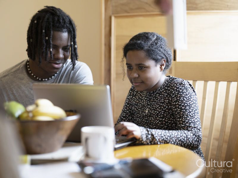 Brother and sister doing homework on laptop at home